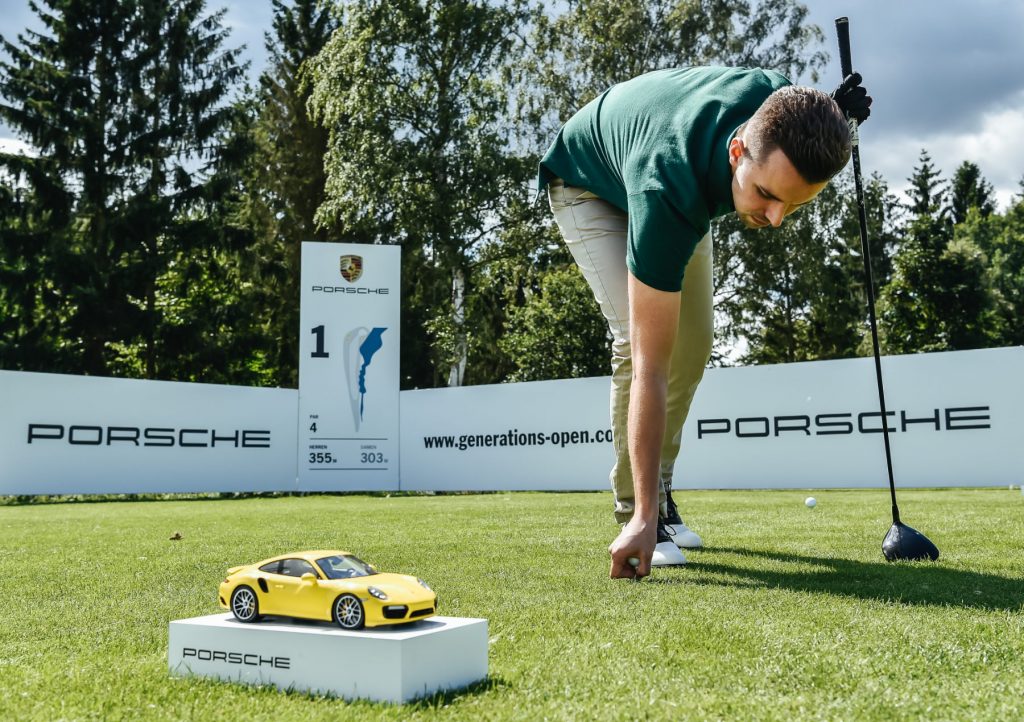 Porsche Generationsopen Golfer mit Ball und Miniporsche