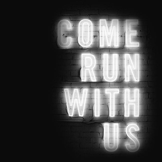 Eine Leuchtreklame mit den Worten "Come run with us". Das nehmen wir wörtlich und erreichen mit unseren Roadshows Menschen auf der ganzen Welt.
